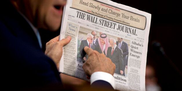 Secretary of State John Kerry points to a photograph on the front page of the Wall Street Journal as an example of cooperation among Arab countries as he testifies on Capitol Hill in Washington, Wednesday, Sept. 17, 2014, during a Senate Foreign Relations Committee hearing on the US strategy to defeat the Islamic State group. (AP Photo/Carolyn Kaster)