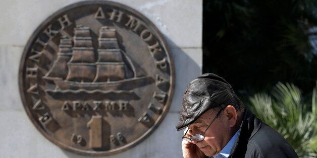 A man walks past a sculpture of Greece's old one-drachma coin in central Athens, on Friday, Feb. 20, 2015. Greece and its European creditors are converging on Brussels to try to bridge major differences over Athens' request for a six-month loan extension to help pay off massive debts. The meeting on Friday is the third among finance ministers from the 19-nation eurozone in just over a week. (AP Photo/Thanassis Stavrakis)