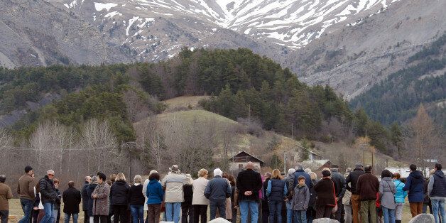 French Red Cross members and inhabitants pay tribute to the victims in front of a stele, a stone slab erected as a monument, set up in the area where a Germanwings aircraft crashed in the French Alps, in Le Vernet, France, Saturday, March 28, 2015. The crash of Germanwings Flight 9525 into an Alpine mountain Tuesday killed all 150 people aboard, and has raised questions about the mental state of the co-pilot. Authorities believe the 27-year-old German deliberately sought to destroy the Airbus A320 as it flew from Barcelona to Duesseldorf. (AP Photo/Claude Paris)
