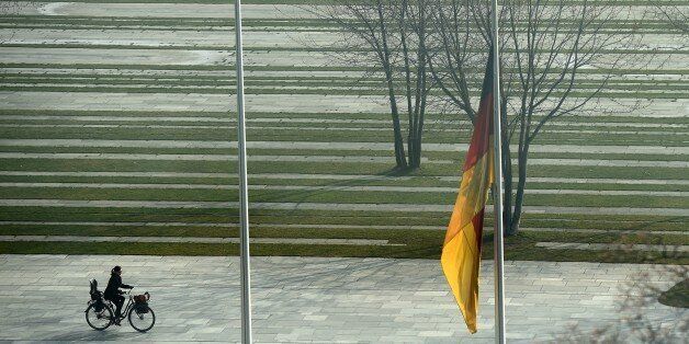 A woman cycles past a German flag flying at half-mast in front of the Chancellery in Berlin March 25, 2015. German Chancellor Angela Merkel will to the French Alpine region where a German passenger plane crashed on March 24, 2015, killing all 150 people on board. Merkel described the news as 'a shock which has plunged us into deep mourning in Germany, France and Spain'. AFP PHOTO / TOBIAS SCHWARZ (Photo credit should read TOBIAS SCHWARZ/AFP/Getty Images)