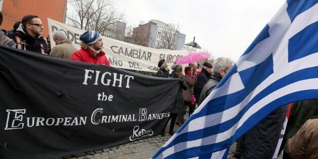 Protestors hold a sign reading 'Fight the European criminal bankers' during a demonstration demanding solidarity with Greece in front of the German Finance Minstry in Berlin, on March 14, 2015. AFP PHOTO / DPA / WOLFGANG KUMM +++ GERMANY OUT (Photo credit should read WOLFGANG KUMM/AFP/Getty Images)