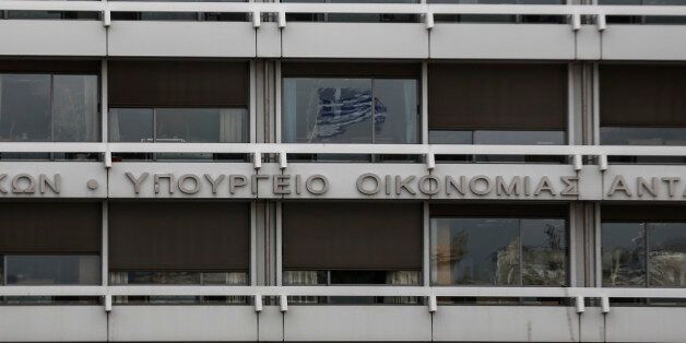 A Greek flag is reflected on a glass window of the Finance Ministry in Athens, Monday, Feb. 23, 2015. Greece will present a list of proposed reforms to debt inspectors on Monday to get final approval for an extension to its rescue loans. But already the government was facing dissent within its ruling party over claims it is backtracking on its promise to ease budget cuts for the recession-battered Greeks. (AP Photo/Yorgos Karahalis)