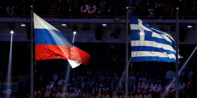 Flagbearers carry the Olympic Flag, as the national flags of Russia, left, and Greece fly during the closing ceremony of the 2014 Winter Olympics, Sunday, Feb. 23, 2014, in Sochi, Russia. The Greek flag is raised to honor the origins of the Olympic Games. (AP Photo/Matthias Schrader)