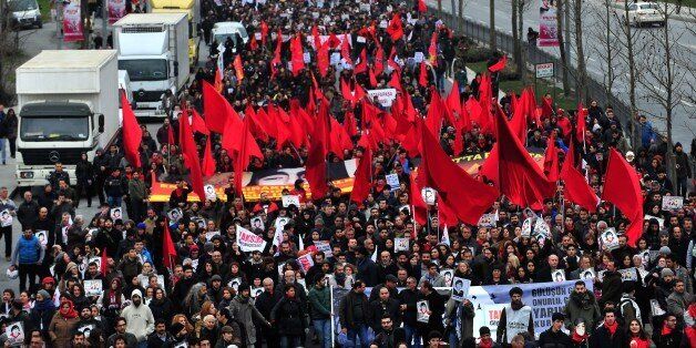 Demostrators march with red flags and posters of Berkin Elvan in Istanbul on March 7, 2015, as thousands of people marched to mark the first anniversary of the death of the youngest victim of the Gezi Park protests. Berkin Elvan was 14-years-old when he was hit by a police teargas canister in Istanbul on June 16, 2013, as anti-government demonstrations swept Turkey. AFP PHOTO/OZAN KOSE (Photo credit should read OZAN KOSE/AFP/Getty Images)