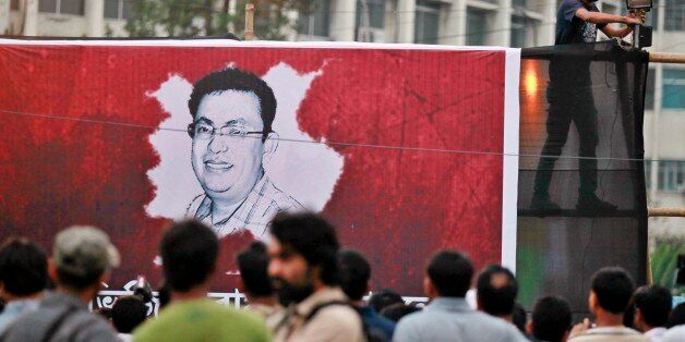 A Bangladeshi activist sets up a light on a poster displaying a portrait of Avijit Roy as others gather during a protest against the Roy in Dhaka, Bangladesh, Friday, Feb. 27, 2015. Roy, a prominent Bangladeshi-American blogger known for speaking out against religious extremism was hacked to death as he walked through Bangladesh's capital with his wife, police said Friday. (AP Photo/A.M. Ahad)
