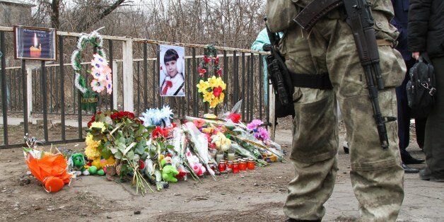 A Ukrainian soldier stands near the place where a Ukrainian armored vehicle ran over a family, killing an 8-year old girl, in Kostyantynivka, Ukraine, Tuesday, March 17, 2015. Residents in the eastern Ukrainian town of Kostyantynivka angrily confronted police officials Tuesday over the accident in which an armored military vehicle struck and killed an 8-year old girl, prompting clashes in front of a dormitory that has been commandeered by soldiers engaged in combat against Russian-backed separat