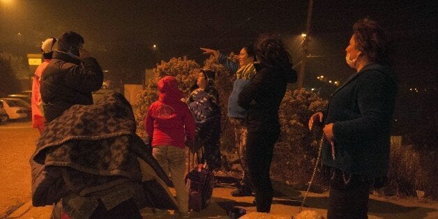 People are seen after being evacuated from their homes in Valparaiso, Chile, due to a forest fire that destroyed about 500 hectares of land and advanced to within just a few miles of the city, on March 13, 2015. Chile declared a state of emergency and precautionary evacuation Friday of up to 16,000 people as a raging forest fire threatened the historic port city of Valparaiso. The fire started in an area of grassland and pine forest near a major thoroughfare connecting Valparaiso -- a UNESCO world heritage site once dubbed 'the jewel of the Pacific' -- with several villages. AFP PHOTO / VLADIMIR RODAS (Photo credit should read VLADIMIR RODAS/AFP/Getty Images)