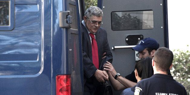 Lawmaker Nikos Mihaloliakos, who leads Greece's Nazi-inspired Golden Dawn party, arrives in handcuffs and with a police escort outside a court in Athens, on Friday, July 4, 2014. Michaloliakos has been in jail since last September pending trial on charges of allegedly running a criminal organization, and on Friday appeared before an investigating judge to answer supplementary arms possession charges. Mihaloliakos denies any wrongdoing. (AP Photo/ Sooc/ Menelaos Myrillas)