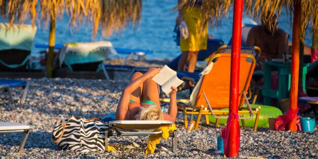 RHODES, GREECE - AUGUST 23: Woman in a bikini is reading and taking a sunbath at the beach in Gennadi on August 23, 2012 in Rhodes, Greece . Rhodes is the largest of the Greek Dodecanes Islands. (Photo by EyesWideOpen/Getty Images)