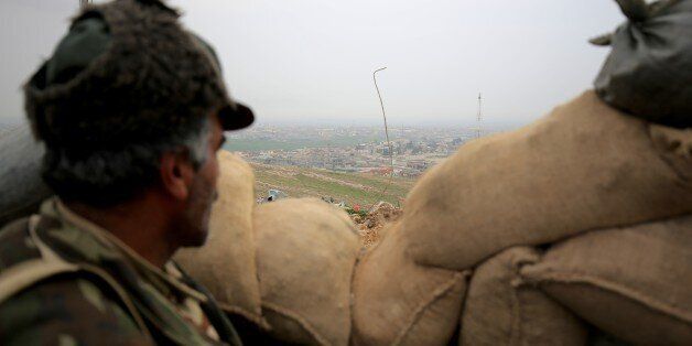 In this Thursday Jan. 29, 2015 photo, a Kurdish peshmerga fighter looks towards the city of Sinjar from behind sand bags in northern Iraq. Peshmerga fighters representing the lawful authorities of Iraqi Kurdistan fume against what they see as the recklessness of their allies in militias drawn from neighboring Syria and Turkey making progress painful and raising doubts about whether these groups can work together. At stake is ownership of Sinjar, the town that once was home to many of Iraqâs Yazidi religious minority. (AP Photo/Bram Janssen)