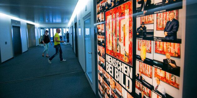 Visitors walk in a corridor as an advertisement for tabloid newspaper Bild, published by Axel Springer SE, stands illuminated inside the company's offices in Berlin, Germany, on Wednesday, June 11, 2014. Axel Springer, Europe's biggest newspaper publisher, is working with JPMorgan Chase & Co. and Citigroup Inc. on an initial public offering of its digital-classifieds business, people familiar with the matter said. Photographer: Krisztian Bocsi/Bloomberg via Getty Images