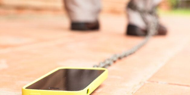 Man walking with smartphone chained to his leg. Conceptual picture for internet addiction.