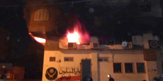 In this image taken with a mobile phone camera late Wednesday, Dec. 5, 2012, bystanders watch as a fire rages at the Muslim Brotherhood office in Ismailia, Egypt. Anti-Mohammed Morsi protesters stormed and set ablaze the Muslim Brotherhood offices in Suez and Ismailia, east of Cairo, and there were clashes in the industrial city of Mahallah and the province of Menoufiyah in the Nile Delta north of the capital. (AP Photo)