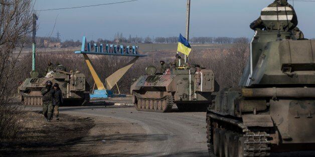 Ukrainian troops ride on armored vehicles towards Artemivsk, eastern Ukraine, Monday, Feb. 23, 2015. A Ukrainian military spokesman says continuing attacks from rebels are delaying Ukrainian forces' pullback of heavy weapons from the front line in the country's east. (AP Photo/Evgeniy Maloletka)