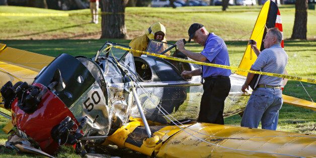 Officials work on the scene of a vintage airplane that crash-landed on the Penmar Golf Course in the Venice area of Los Angeles, Thursday, March 5, 2015. Harrison Ford crash-landed the airplane shortly after taking off from a nearby airport and reporting engine problems. (AP Photo/Damian Dovarganes)