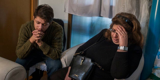 Rafaela Santiago Salazar, 53, right, and her son Rafael, left, pray as riot police surround the apartment to evict them, in Madrid, Spain, Friday, Feb. 20, 2015. Rafaela Santiago Salazar, who is unemployed and lives with her 18 year old son, suffers from fibromyalgia and survives on a low income of euros 468 ($531) from state benefits. They occupied the apartment 5 years ago as they could not afford to rent a place due to their financial situation. They were trying to negotiate to pay a low pro