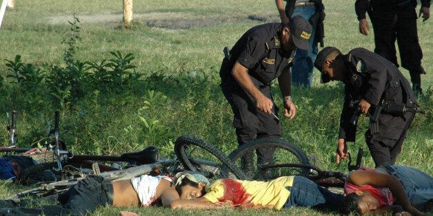 EDS. NOTE GRAPHIC CONTENT.- Police officers inspect the bodies of the victims of a massacre at a soccer field in San Pedro Sula, Honduras, Saturday Oct. 30, 2010. A carful of attackers armed with assault rifles drove up to the football field Saturday and opened fire, killing at least 14 people.(AP Photo)
