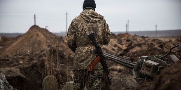 BERDIANSKE, UKRAINE - FEBRUARY 28: A Ukrainian soldier stands next to newly dug trenches near the front line of defense against pro-Russian seperatists on February 28, 2015 near in the village of Berdianske, Ukraine. Berdianske is on the eastern side of Mariupol, Ukraine - many Ukrainian soldiers believe pro-Russian seperatists will try to take control of the city of Mariupol next in an effort to create a land bridge between Russia and Crimea. (Photo by Andrew Burton/Getty Images)