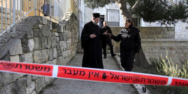 A Greek Orthodox priest talks to Israeli policewoman outside a seminary in Jerusalem, Thursday Feb. 26, 2015. The Greek Orthodox seminary was damaged in fire and anti-Christian slogans were written in Hebrew, in what Israeli police said the suspect was a hate crime. (AP Photo/Mahmoud Illean)