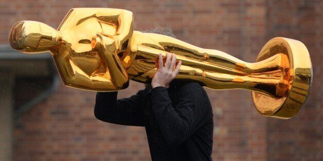 A worker carries an Oscar statue to a press event held by Filmstudios Babelsberg in Potsdam, eastern Germany following the sucess of the 'Grand Budapest Hotel' at the Oscars on February 23, 2015. The film, which was awarded 4 Oscars, Best original soundtrack, Best costume design, Best make-up / hairstyling and Best production design, was co-produced by Filmstudios Babelsberg. AFP PHOTO / DPA / RALF HIRSCHBERGER +++ GERMANY OUT +++ (Photo credit should read RALF HIRSCHBERGER/AFP/Getty Im