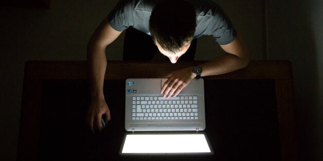 Guy checking internet with laptop at late night with dark room, view from above. Internet addiction.