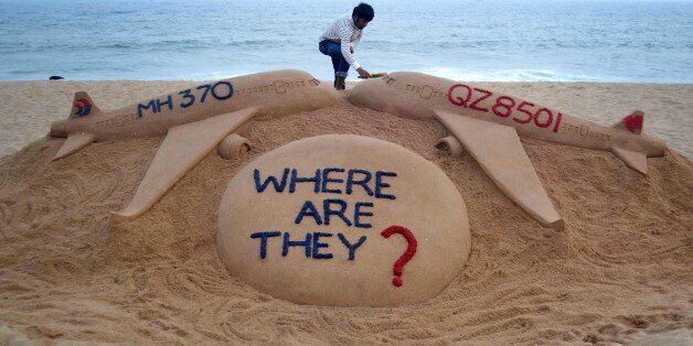Indian sand artist Sudarsan Pattnaik gives the final touches to his sand sculpture portraying two missing aircraft, Air Asia QZ8501 and Malayasia Airlines MH370 on Golden Sea Beach at Puri, some 65 kms east of Bhubaneswar on December 29, 2014. An AirAsia Airbus plane with 162 people on board went missing en route from Surabaya in Indonesia to Singapore early on December 28, officials and the airline said, in the third major incident to affect a Malaysian carrier this year. AFP PHOTO/STR