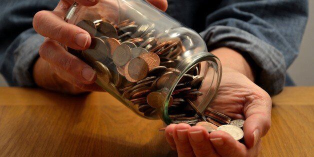 A person is seen emptying a money savings jar into their hand to count the contents.