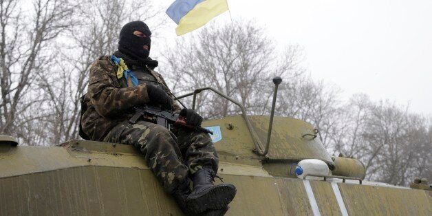 An Ukrainian soldier rests on his vehicle near the road between the towns of Debaltseve and Artemivsk, Ukraine, Monday, Feb. 16, 2015. The Ukrainian government and Russia-backed rebels accused each other Monday of violating a cease-fire in eastern Ukraine, a day before the parties are due to start withdrawing heavy weaponry under a recently brokered deal. The cease-fire, which went into effect on Sunday, had raised cautious hopes for an end to the 10-month-old conflict, which has already claime