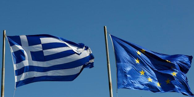 A Greek national flag, left, flies alongside a European Union (EU) flag in Athens, Greece, on Thursday, Feb. 19, 2015. Germany rebuffed Greece's request for an extension of its aid program, saying the Greek offer doesn't meet the euro region's conditions for continuing aid. Photographer: Kostas Tsironis/Bloomberg via Getty Images