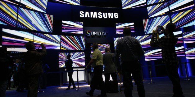 Attendees view Samsung Electronics Co. SUHD 4K televisions during the 2015 Consumer Electronics Show (CES) in Las Vegas, Nevada, U.S., on Tuesday, Jan. 6, 2015. This year's CES will be packed with a wide array of gadgets such as drones, connected cars, a range of smart home technology designed to make everyday life more convenient and quantum dot televisions, which promise better color and lower electricity use in giant screens. Photographer: Patrick T. Fallon/Bloomberg via Getty Images
