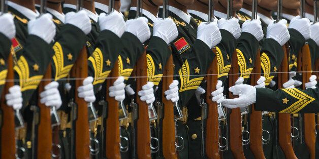 A Chinese People's Liberation Army soldier adjusts a rifle of a member of an honor guard as they prepare for a welcome ceremony for visiting Spanish Prime Minister Mariano Rajoy outside the Great Hall of the People in Beijing, China Thursday, Sept. 25, 2014. (AP Photo/Andy Wong)
