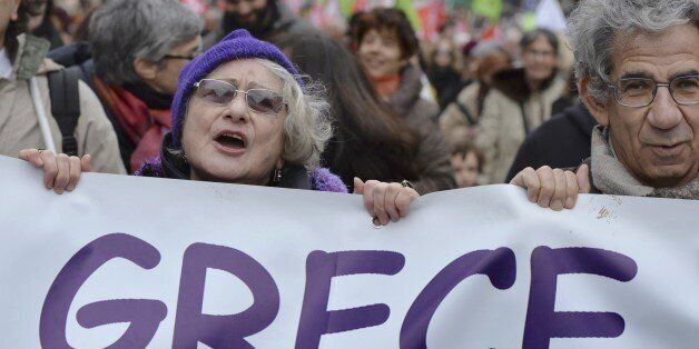 Protesters hold a banner during a demonstration in support of the Greek people on February 15, 2015 in Paris. At least 2,000 people marched through the streets of Paris on February 15 heeding the call from unions and far-left organisations to voice their support for Greece and its new leftist anti-austerity government. AFP PHOTO / LOIC VENANCE (Photo credit should read LOIC VENANCE/AFP/Getty Images)