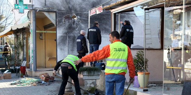 Police officers check the site of an explosion at a drug store, left, belonging to Interior Minister Saimir Tahiriâs father and the neighboring house damaged overnight in Tirana, Albania,Tuesday, Feb. 10, 2015. Another explosion rocked the apartment of a top police officer while anti-mine experts blasted with remote control two TNT explosive ingots found downtown capital. (AP Photo/Hektor Pustina))