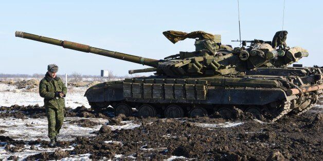 In this Wednesday, Jan. 14, 2015 photo Russian-backed separatist walks past tanks at the check-point north of Luhansk, Eastern Ukraine. An attack on a passenger bus in eastern Ukraine killed 12 people Tuesday, likely dealing the final blow to hopes that a short-lived and shaky cease-fire could take hold. (AP Photo/ Mstyslav Chernov)