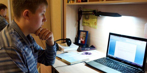 In this photo taken on Friday, Nov. 28, 2014, Denis Akimov, 15, sits in front of his laptop at home in Donetsk, eastern Ukraine. Like most children his age, Denis Akimov spends hours daily on his computer surfing the Internet. It isnât just for fun. As schools are forced to limit operations in the conflict-battered eastern Ukrainian city of Donetsk, educators are turning to the Web to keep their charges learning. (AP Photo/Balint Szlanko)