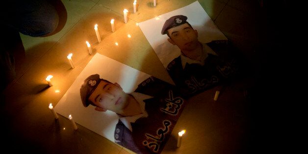 Members of Al-Kaseasbeh, the tribe of Jordanian pilot, Lt. Muath al-Kaseasbeh, who is held by the Islamic State group militants, light candles by posters with his picture and Arabic that reads