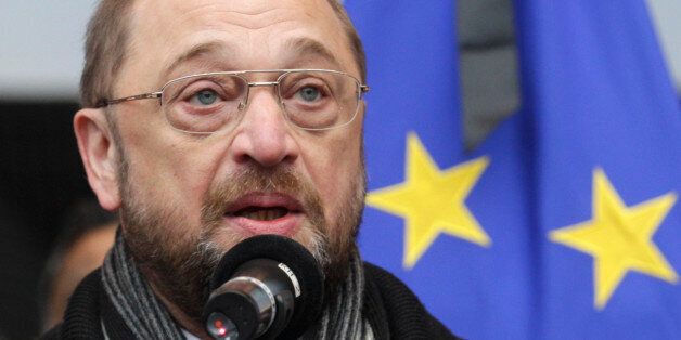 European Parliament President Martin Schulz shows a sticker that reads: 'Je suis Charlie (I Am Charlie)', during a gathering to pay respect to the victims of Wednesday's terror attack in Paris, in front of the European Parliament in Brussels, Thursday, Jan. 8, 2015. Eight journalists, two police officers, a maintenance worker and a visitor were killed, and eleven people wounded in a terrorist attack against French satirical newspaper Charlie Hebdo in Paris. (AP Photo/Yves Logghe)