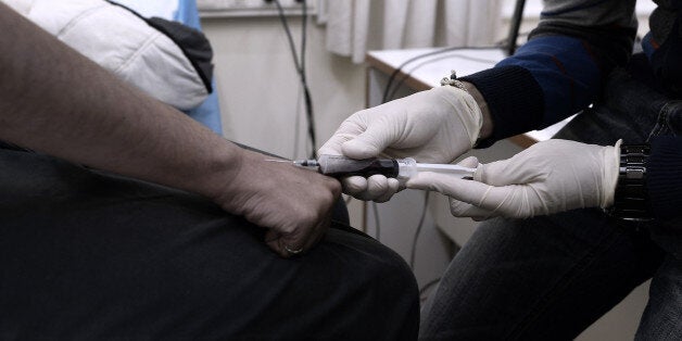 A drug addict gives a blood sample on November 25, 2013 in Athens as she gets tested for HIV, in a program launched in August 2012 by the Greek Okana NGO and funded by the European Union. Okana also launched Greece's first ever consumption room, where people addicted to hard drugs can shoot under supervision, which has been running as a pilot project for more than a month and so far has between five and twelve visitors every day. AFP PHOTO / ARIS MESSINIS (Photo credit should read ARIS ME