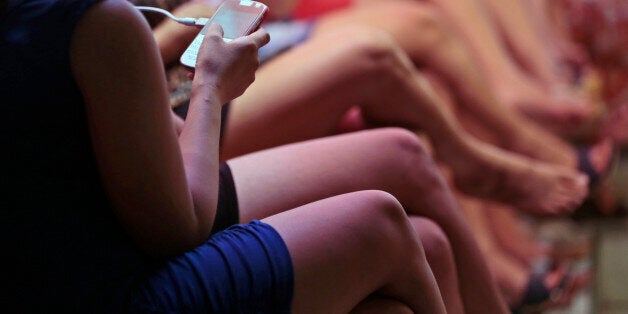 In this Thursday, June 19, 2014 photo, a sex worker checks her smartphone as she and others wait for customers in a brothel at Dolly prostitution complex in Surabaya, Indonesia. The mayor of Indonesia's second-largest city may have officially shut down one of Southeast Asia's biggest red-light districts areas last week, but the world's oldest profession is still up and running despite warnings to stop. (AP Photo/Dita Alangkara)