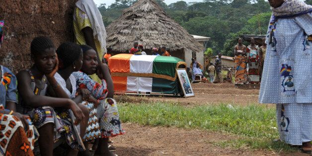 Residents gather around the coffin of slain General Robert Guei, during a burial ceremony attended by Ivory Coast President Laurent Gbagbo (unseen) in Kabakouma on October 2, 2009. The ex-junta General was assasinated on September 19th, 2002, the day of his failed military coup against President Laurent Gbagbo. The circumstances of his death are still unclear. AFP PHOTO/ SIA KAMBOU (Photo credit should read SIA KAMBOU/AFP/Getty Images)