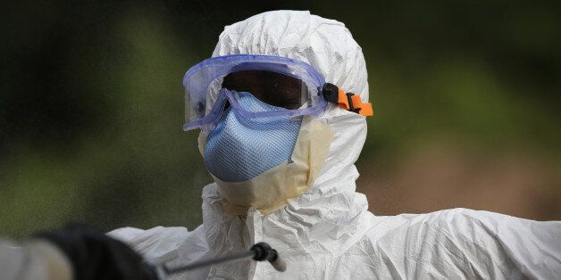 DISCO HILL, LIBERIA - JANUARY 27: A burial team member wearing personal protective equipment (PPE), stands for decontamination spray at the U.S.-built cemetery for 'safe burials' on January 27, 2015 in Disco Hill, Liberia. The cemetery, operated by USAID-funded Global Communities, has buried almost 300 people in its first month of operation, with increasingly fewer of the bodies coming from Ebola Treatment Units (ETUs), as infection rates decline. The cemetery, where burial team members wear protective clothing, has been seen in Monrovia as a major achievement, as families of deceased loved ones are permitted to view the burials, important in Liberian culture. In an effort to control the Ebola epidemic in 2014, the Liberian government had ordered the cremation of all deceased in the capital, often further traumatizing surviving family members and unintentionally encouraging many families to hide their dead for secret burials. (Photo by John Moore/Getty Images)