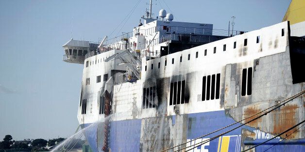 BRINDISI, ITALY - JANUARY 07: The hull of the burned-out ferry 'Norman Atlantic' is cooled by firemen as it stands moored in port on January 07, 2015 in Brindisi, Italy. Yesterday firemen have measured the temperature on the ferry in order to give permission to the police investigators to go aboard and to find out the cause of the fire, but it is still unclear when investigators will access the ferry. So far police has been unable to gain access deep inside the vessel in the their search for more bodies as temperatures inside the hull from the fire that struck the ship remain too high and heavy winds hit the coast of south-east Italy. The Italian-owned ferry caught fire on December 28, 2014, on its journey from Patras in Greece to Ancona in Italy. At least 11 people are confirmed dead as a result of the blaze and 477 survived after being rescued by the Italian Coast Guard and Navy, though 19 passengers remain unaccounted for and are presumed to likely be dead and still inside the ship. (Photo by Alexander Koerner/Getty Images)