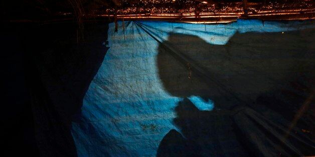 Shadow of a man praying is cast on the cover of a makeshift tent at