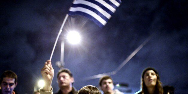 A young child waves the national flag as crowds gather in front of the Greek parliament in Athens on February 5, 2015 in support of the new anti-austerity government's efforts to renegotiate Greece's international loans. About 5,000 people gathered in Syntagma Square, police said, in front of the Greek parliament, the site of violent protests at the height of the Greek crisis in 2012. Many praised the government for 'defending the interests' of the Greek people. AFP PHOTO/ Louisa Gouliamaki (Photo credit should read LOUISA GOULIAMAKI/AFP/Getty Images)