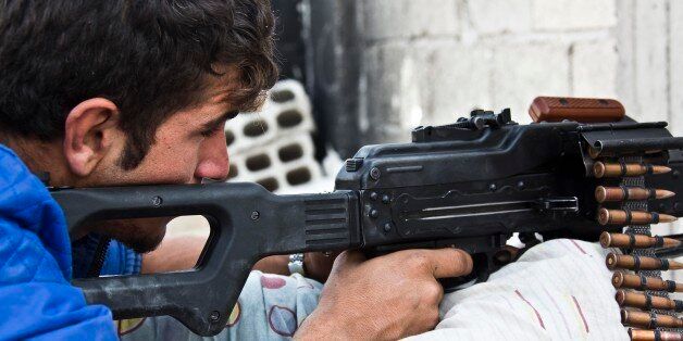 In this Wednesday, Nov. 19, 2014 photo, a young Kurdish People's Protection Units (YPG) fighter who recently volunteered holds a position with a PKM in Kobani, Syria. Here, Kurdish fighters backed by small numbers of Iraqi peshmerga forces and Syrian rebels, are battling what they see as an existential battle against the militants who swept into their town in mid-September as part of a summer blitz that saw the group seize large chunks of territory in Syria and neighboring Iraq.(AP Photo/Jake Simkin)