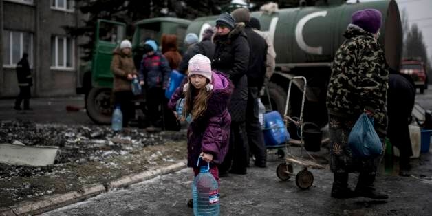 A girl holds a water bottle in the town of Debaltseve, eastern Ukraine, Friday, Feb. 6, 2015. Pro-Russia rebels and the Ukrainian authorities agreed Friday on a humanitarian corridor to evacuate civilians from the epicenter of fighting in eastern Ukraine as German and French leaders prepared to bring their peace plan to Moscow. (AP Photo/Evgeniy Maloletka)