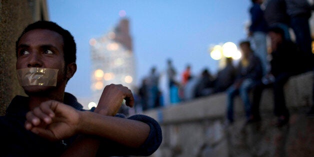 An African migrant covers his mouth with tape during a protest in front of the U.S. embassy demanding asylum and work rights from the Israeli government in Tel Aviv, Israel, Wednesday, Jan. 22, 2014. About 60,000 African migrants, mostly from Sudan and Eritrea, have trekked through Egypt and other Muslim countries to reach Israel in recent years. Some are fleeing violence or oppression in their home countries while others are seeking better economic opportunities in Israel. (AP Photo/Oded Balilt