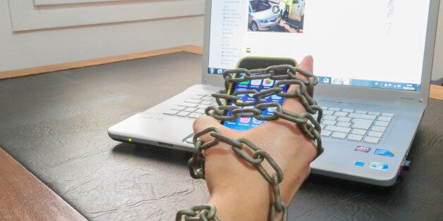 Guy chained to smartphone and internet laptop. Conceptual picture for internet addiction.