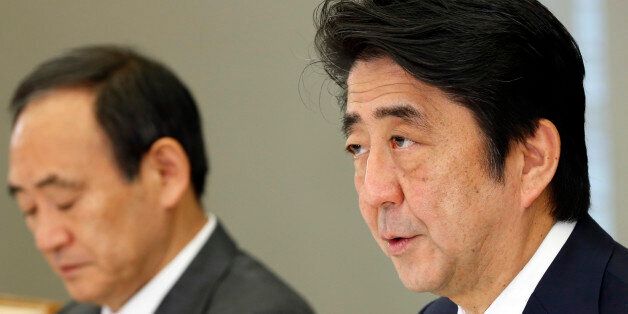 Japan's Prime Minister Shinzo Abe, right, accompanied by government spokesman Yoshihide Suga, speaks during a hurriedly held ministerial meeting on Japanese hostage Kenji Goto taken by the Islamic State group, at the prime minister's official residence in Tokyo Thursday, Jan. 29, 2015. The extremist group released a message late Wednesday purportedly extending the deadline for Jordan's release of an Iraqi would-be hotel bomber linked to al-Qaida. The message, read by a voice claiming to be Goto, was released online after Jordan offered a precedent-setting prisoner swap to the Islamic State group, desperately seeking to save a Jordanian air force pilot the militants purportedly threatened to kill, along with Goto. Suga said on Thursday the government was analyzing the latest message and Japan was doing its utmost for the release of Goto, working with nations in the region, including Turkey, Jordan and Israel. (AP Photo/Shizuo Kambayashi, Pool)