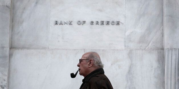 A man walks past the Bank of Greece headquarters, in central Athens, on Wednesday, Feb. 4, 2015. With all Europe waiting to see how Greece proposes to renegotiate its massive bailout loans, Greece's Prime Minister Alexis Tsipras and his Finance Minister Yanis Varoufakis are on a whirlwind tour of the region to discuss possible solutions. Tsipras wants easier terms of repayment on the 240 billion euros (currently $271 billion) in bailout loans and to ease back on the austerity budget measures th